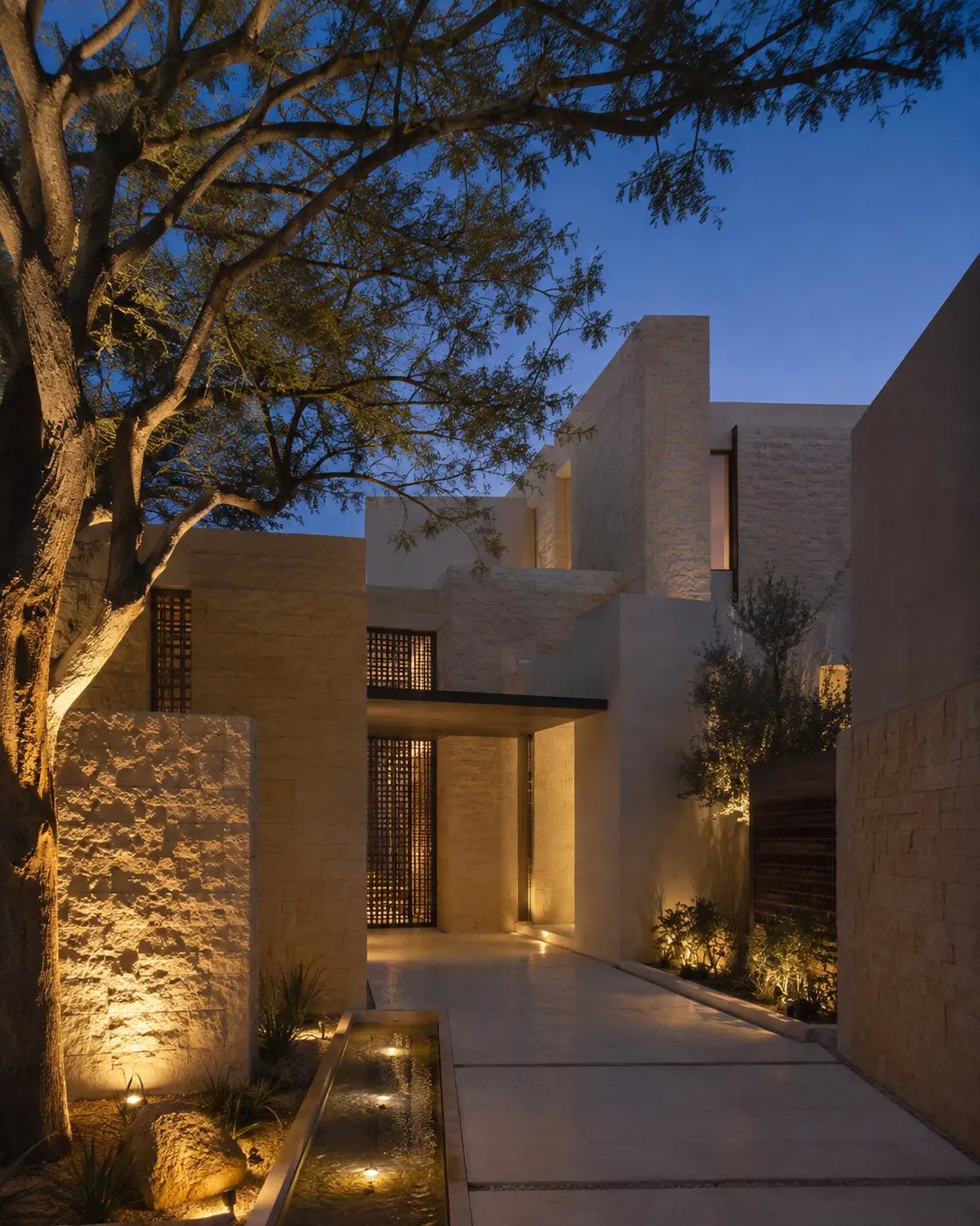 Illuminated limestone entrance and mature courtyard tree at a private Jumeirah residence