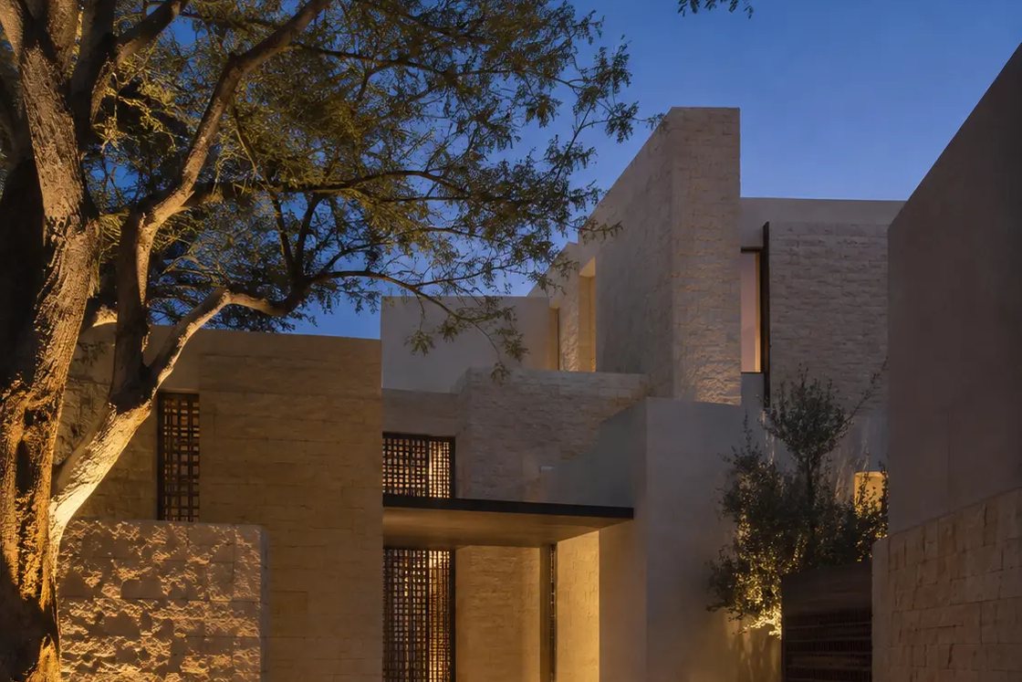 Illuminated limestone entrance and mature courtyard tree at a private Jumeirah residence